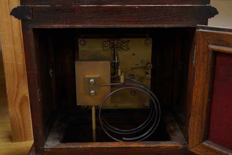 An early 20th century carved oak mantel clock, with key and pendulum, 58cm high